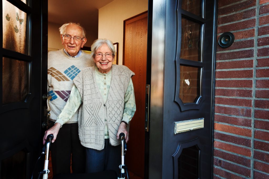 Older couple standing a front door ready to receive meals on wheals