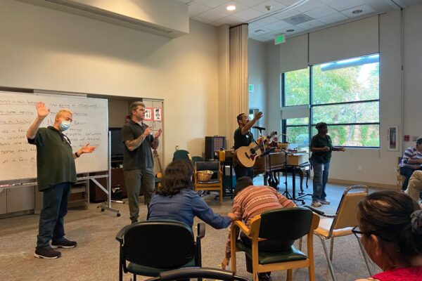 Group performing music. Three people are dancing. One person is playing the guitar.