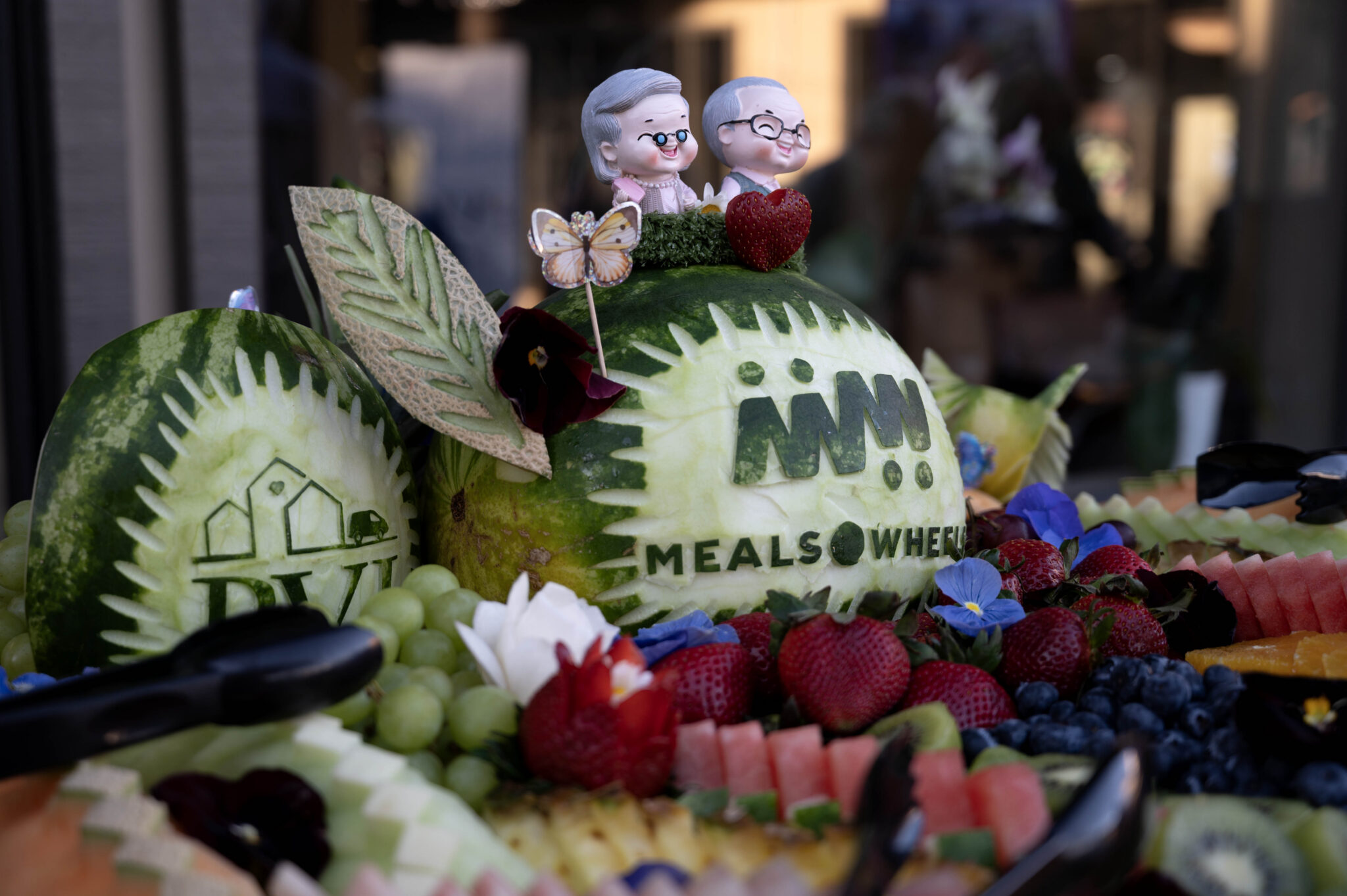 Two senior toppers sit on top a fruit display at PVI's annual March for Meals Community Champions Breakfast at PVI’s Adult Activity Center at Little House in Menlo Park, Calif. on Thursday, March 19, 2026. Photo by Karina Patel.